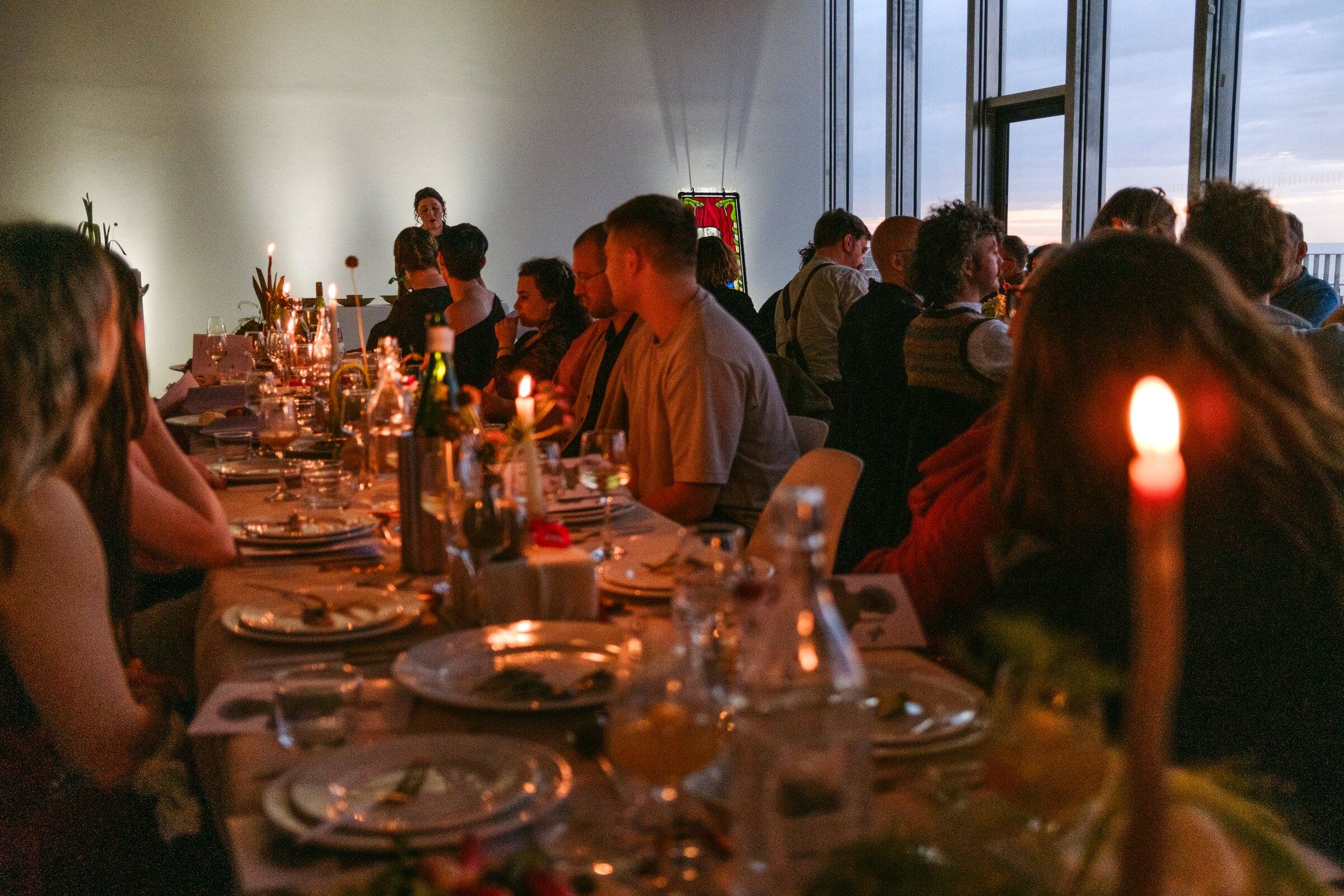 Candlelit tables crowded with diners, plates and glasses.