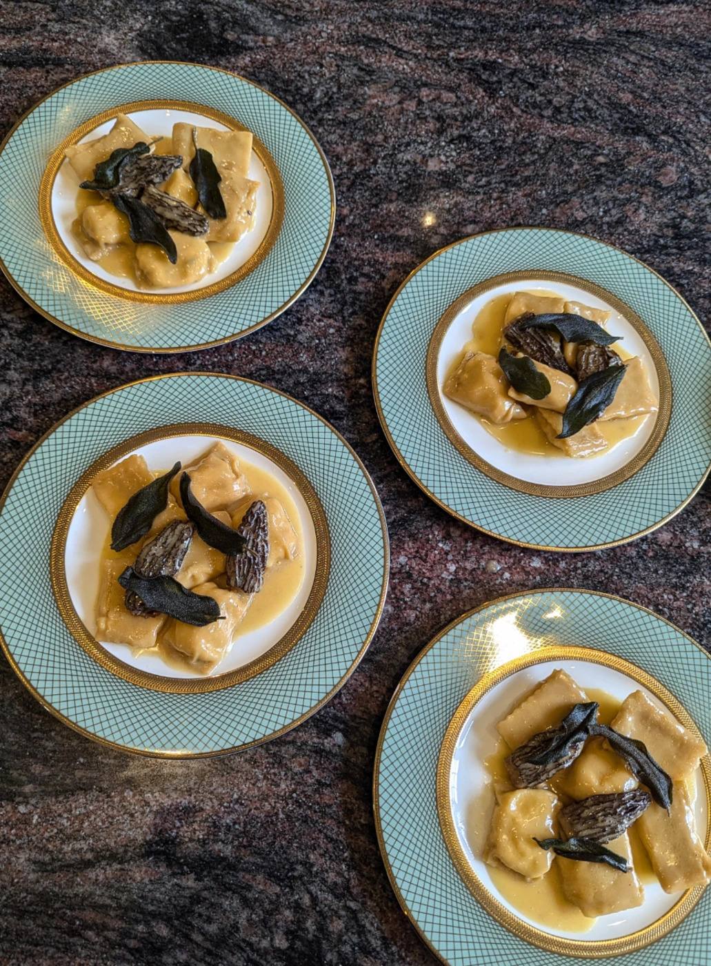 Plates of ravioli with morels on pale blue and gold china.